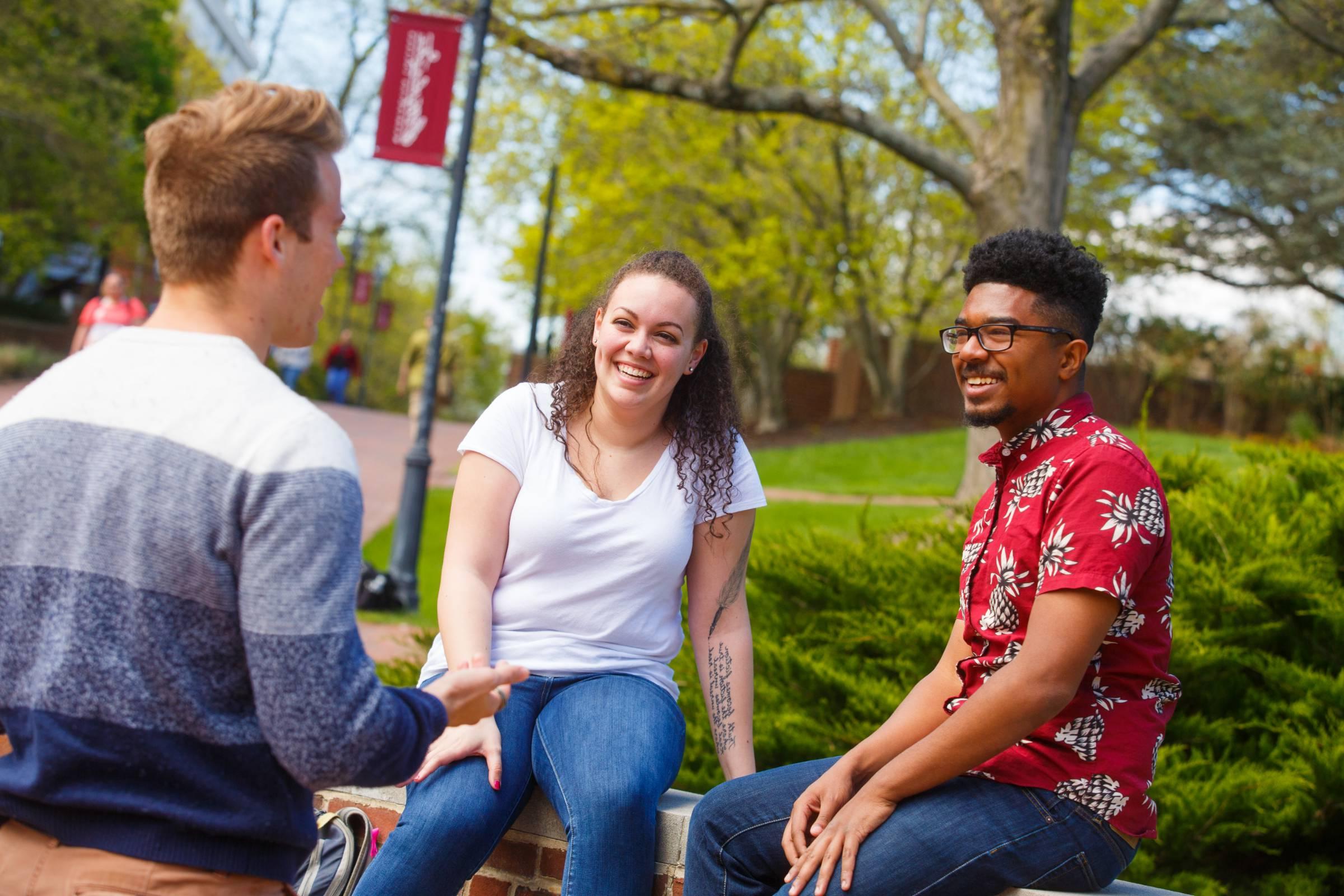 three students sitting on a bench outside